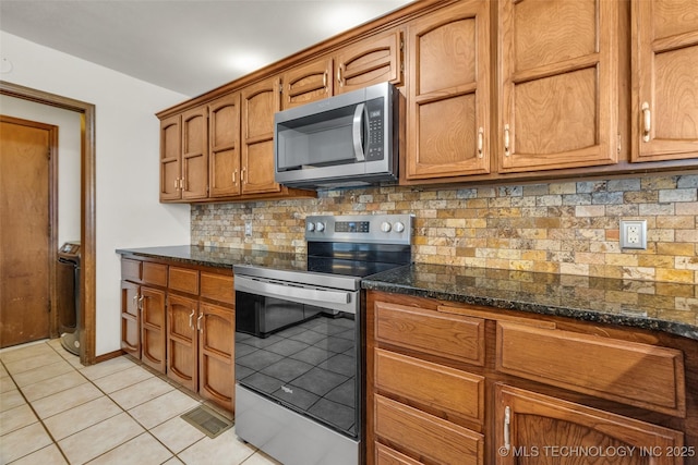 2847 W 115th Pl S, Jenks, OK 74037 - kitchen featuring appliances with stainless steel finishes, light tile patterned floors, tasteful backsplash, and dark stone countertops