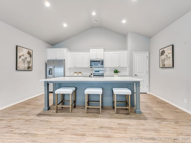 7809 S Redbud Ave, Broken Arrow, OK 74011 - kitchen featuring appliances with stainless steel finishes, a large island, decorative backsplash, white cabinets, and high vaulted ceiling