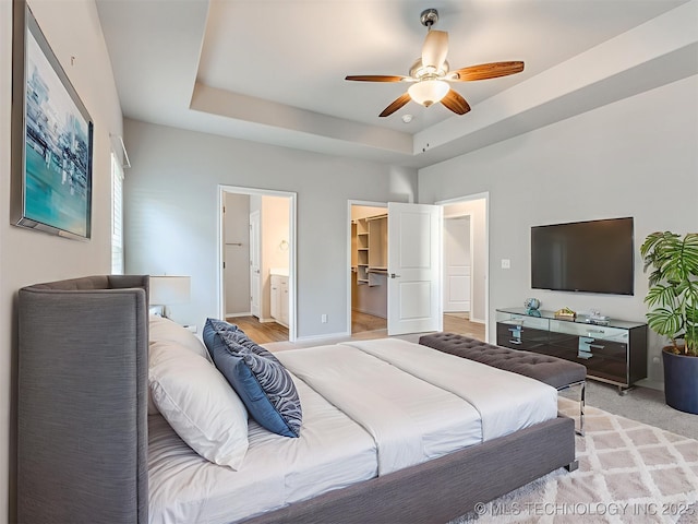 7809 S Redbud Ave, Broken Arrow, OK 74011 - bedroom featuring a walk in closet, a ceiling fan, connected bathroom, and a tray ceiling