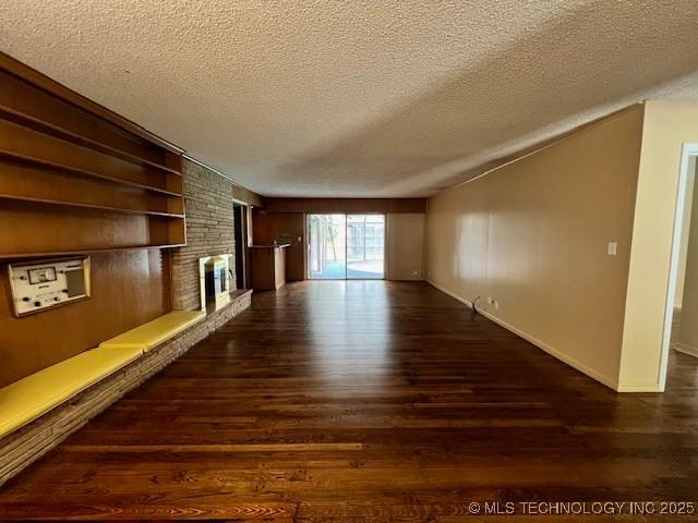 3707 Canton Ave, Tulsa, OK 74135 - unfurnished living room featuring a textured ceiling, wood finished floors, and a brick fireplace