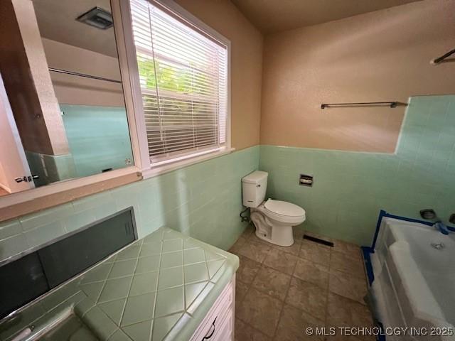 3707 Canton Ave, Tulsa, OK 74135 - full bath featuring a bathtub, tile walls, and a wainscoted wall