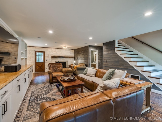 7001 S Redbud Ave, Broken Arrow, OK 74011 - living area with a large fireplace, dark wood-type flooring, recessed lighting, stairs, and wood walls
