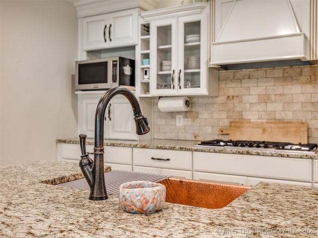 7001 S Redbud Ave, Broken Arrow, OK 74011 - kitchen featuring custom range hood, light stone countertops, decorative backsplash, white cabinetry, and stainless steel gas cooktop
