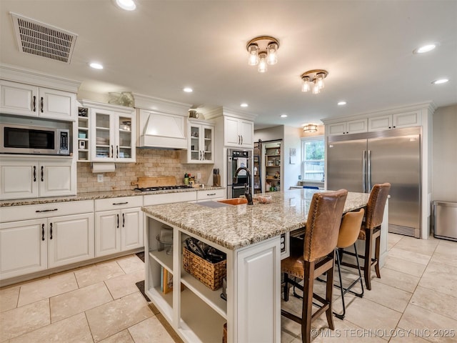 7001 S Redbud Ave, Broken Arrow, OK 74011 - kitchen with appliances with stainless steel finishes, custom exhaust hood, light tile patterned floors, backsplash, and recessed lighting
