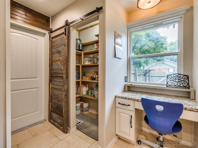 7001 S Redbud Ave, Broken Arrow, OK 74011 - home office featuring light tile patterned floors, built in study area, and a barn door