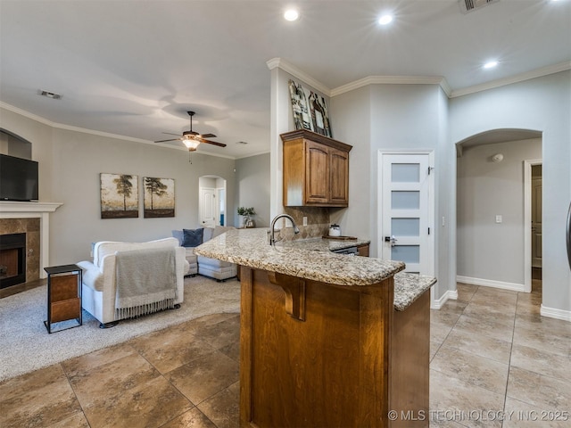 2603 S 16th Pl, Broken Arrow, OK 74012 - kitchen featuring arched walkways, a peninsula, light stone counters, a ceiling fan, and a breakfast bar