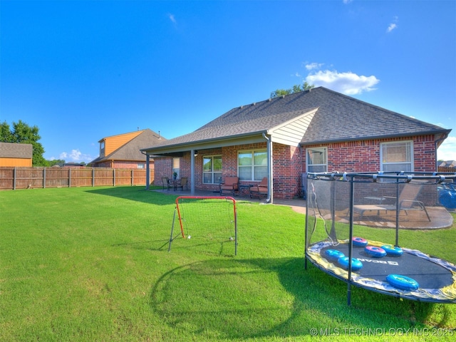 2603 S 16th Pl, Broken Arrow, OK 74012 - back of house with brick siding, a fenced backyard, a trampoline, a patio area, and a shingled roof