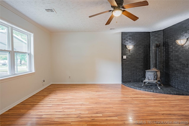 11598 E Oak St, Claremore, OK 74019 - unfurnished living room with a textured ceiling, light wood-type flooring, a wood stove, and a ceiling fan
