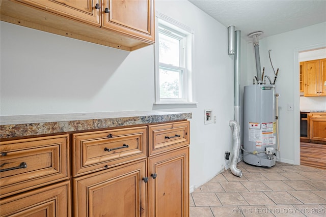 11598 E Oak St, Claremore, OK 74019 - laundry room featuring water heater, cabinet space, hookup for a washing machine, and light tile patterned floors