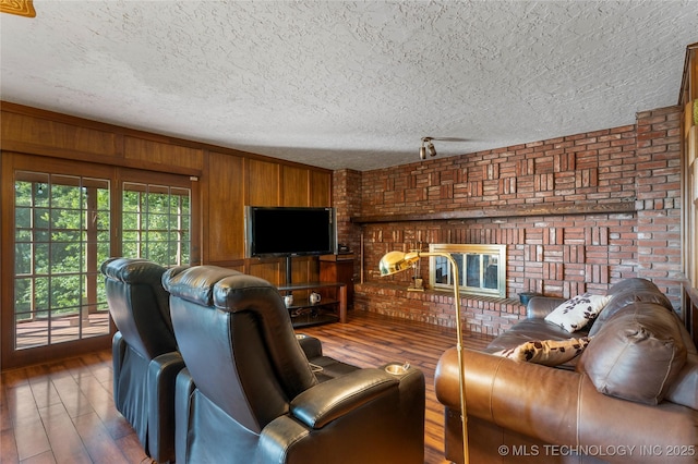17304 E 176th St S, Bixby, OK 74008 - living room featuring hardwood / wood-style floors, wooden walls, a textured ceiling, and a brick fireplace
