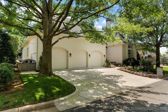 2524 E 66th Pl, Tulsa, OK 74136 - view of front of home featuring concrete driveway, a garage, a chimney, and stucco siding