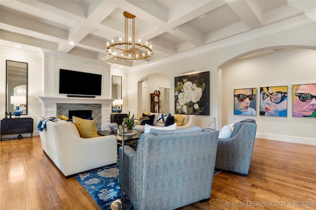 2524 E 66th Pl, Tulsa, OK 74136 - living room with arched walkways, coffered ceiling, a high end fireplace, wood finished floors, and beamed ceiling