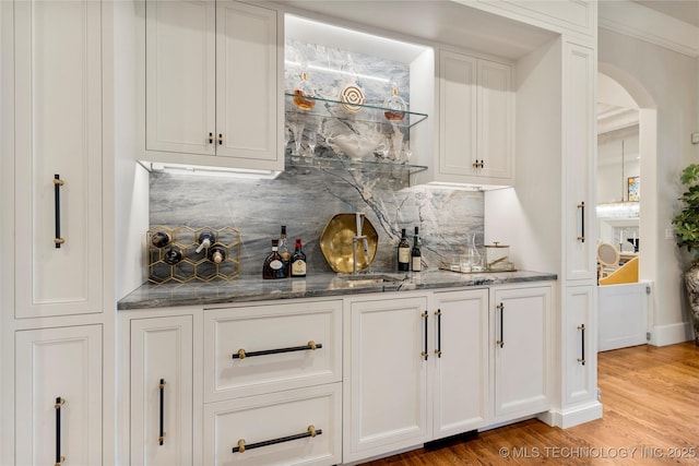2524 E 66th Pl, Tulsa, OK 74136 - indoor wet bar with arched walkways, backsplash, and light wood-style flooring