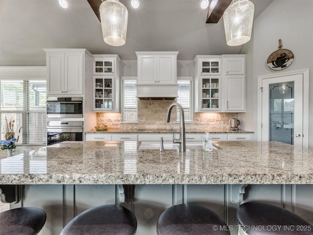 5509 E 121st Pl S, Tulsa, OK 74008 - kitchen featuring oven, backsplash, white cabinetry, and a breakfast bar