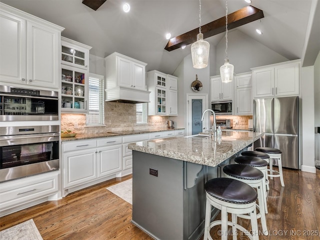 5509 E 121st Pl S, Tulsa, OK 74008 - kitchen with black appliances, vaulted ceiling, white cabinets, a kitchen bar, and light stone countertops