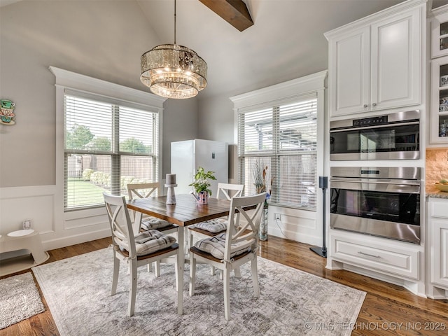 5509 E 121st Pl S, Tulsa, OK 74008 - dining room featuring a chandelier, wood finished floors, a wainscoted wall, plenty of natural light, and high vaulted ceiling