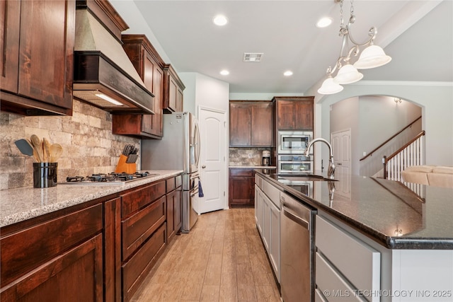 6904 S Chestnut Ave, Broken Arrow, OK 74011 - kitchen featuring premium range hood, appliances with stainless steel finishes, tasteful backsplash, a center island with sink, and light wood-type flooring