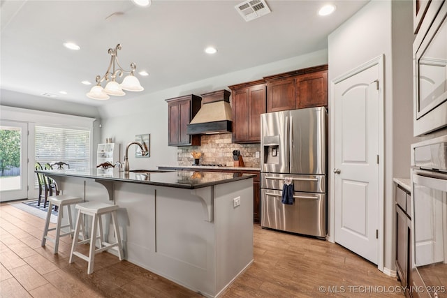 6904 S Chestnut Ave, Broken Arrow, OK 74011 - kitchen with stainless steel fridge with ice dispenser, custom exhaust hood, a kitchen breakfast bar, light wood finished floors, and recessed lighting