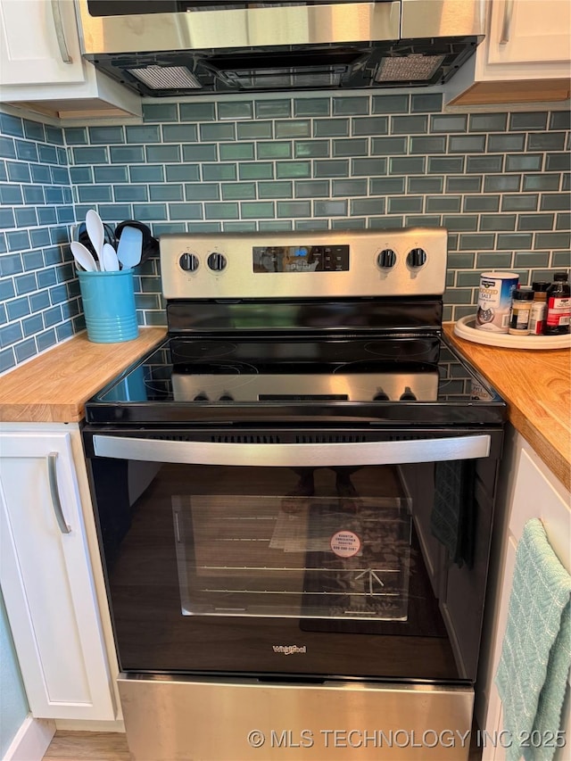 33455 State Highway 82, Cookson, OK 74427 - kitchen view of stainless steel electric range oven, wood counters, backsplash, and white cabinetry