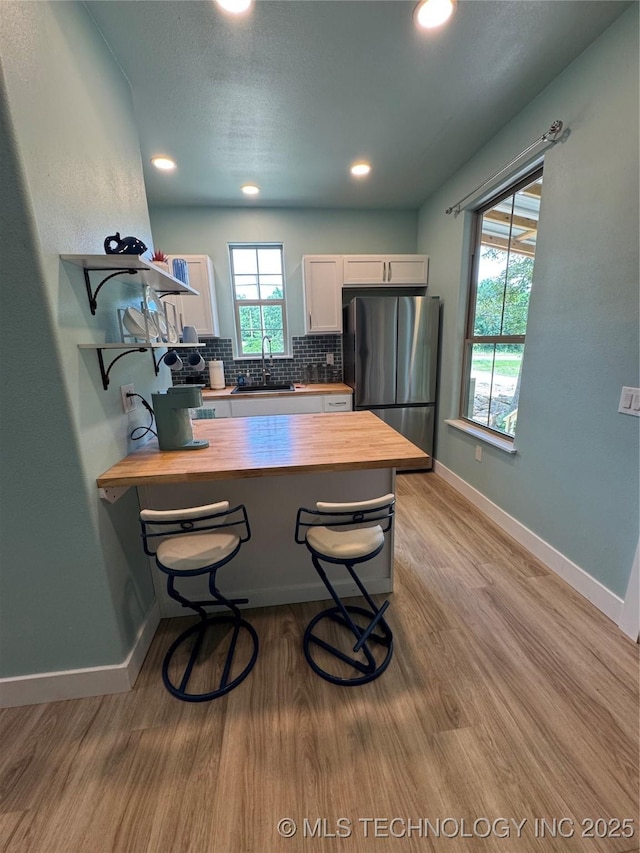 33455 State Highway 82, Cookson, OK 74427 - kitchen featuring freestanding refrigerator, wooden counters, a peninsula, light wood-style flooring, and decorative backsplash