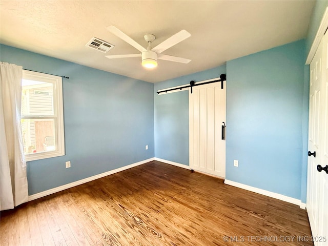 206 S 2nd St, Eufaula, OK 74432 - unfurnished bedroom with a barn door, wood finished floors, and ceiling fan