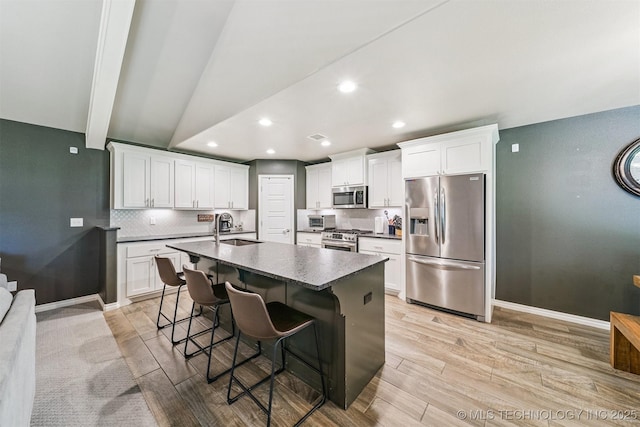8035 Tims Ln, Claremore, OK 74019 - kitchen featuring appliances with stainless steel finishes, light wood-style floors, a kitchen bar, recessed lighting, and an island with sink