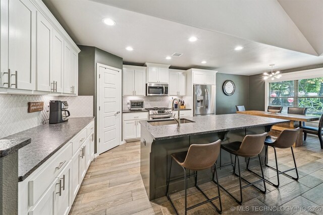 8035 Tims Ln, Claremore, OK 74019 - kitchen featuring appliances with stainless steel finishes, recessed lighting, a breakfast bar, a kitchen island with sink, and white cabinets