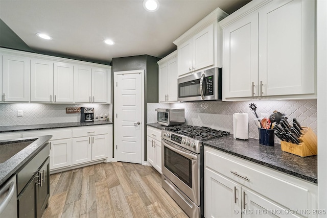 8035 Tims Ln, Claremore, OK 74019 - kitchen with stainless steel appliances, white cabinets, light wood-type flooring, dark stone counters, and recessed lighting