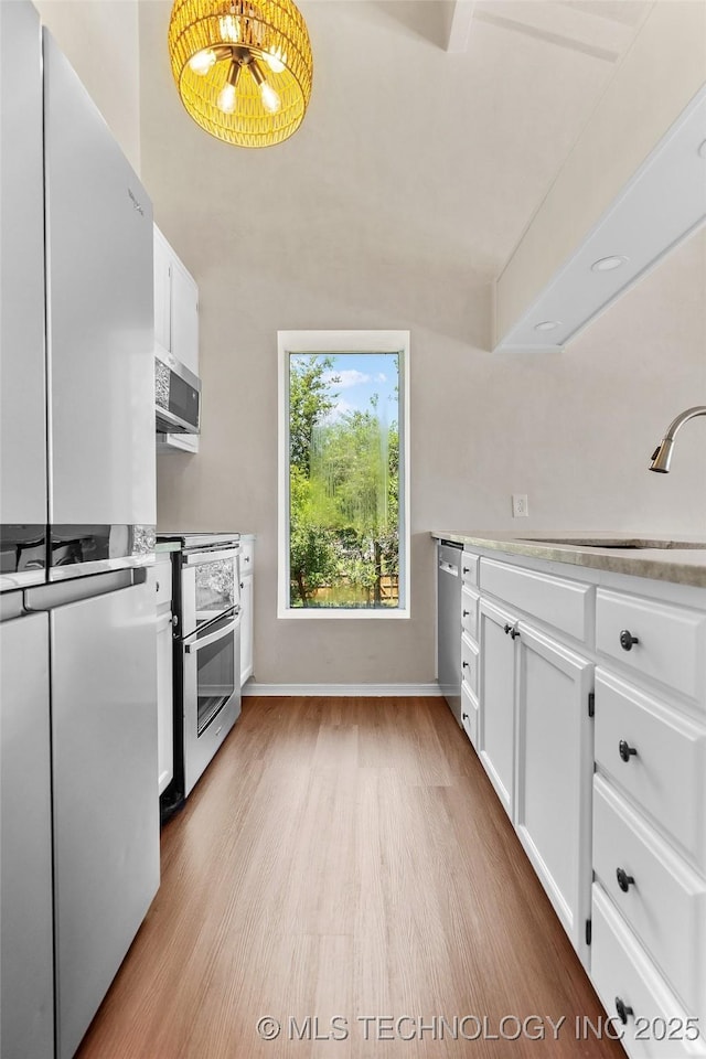 2807 E 90th St Unit 4, Tulsa, OK 74137 - kitchen featuring appliances with stainless steel finishes, light wood-style floors, white cabinets, and light countertops