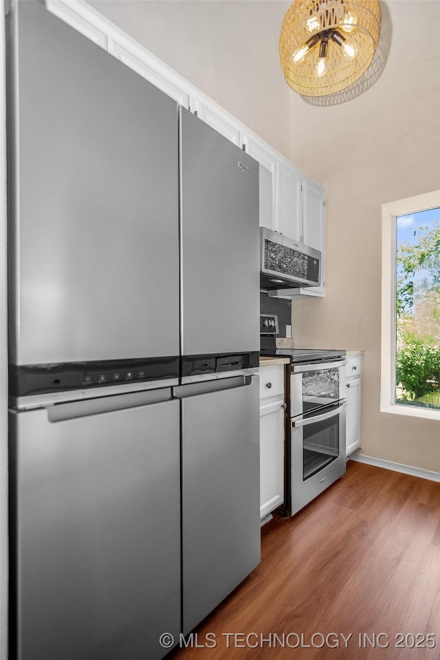 2807 E 90th St Unit 4, Tulsa, OK 74137 - kitchen with appliances with stainless steel finishes, wood finished floors, white cabinets, a chandelier, and a towering ceiling