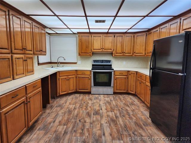 10 W Midland, Shawnee, OK 74804 - kitchen with freestanding refrigerator, stainless steel electric range, and brown cabinetry