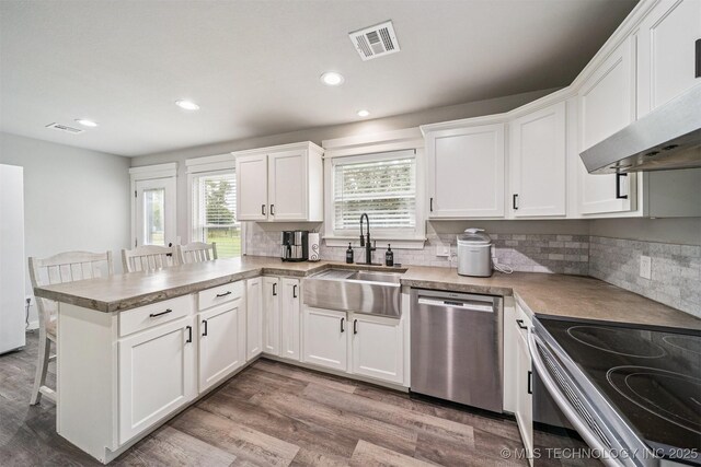 12929 N Sheridan Rd, Collinsville, OK 74021 - kitchen with dishwasher, range with electric cooktop, a peninsula, a breakfast bar area, and white cabinets