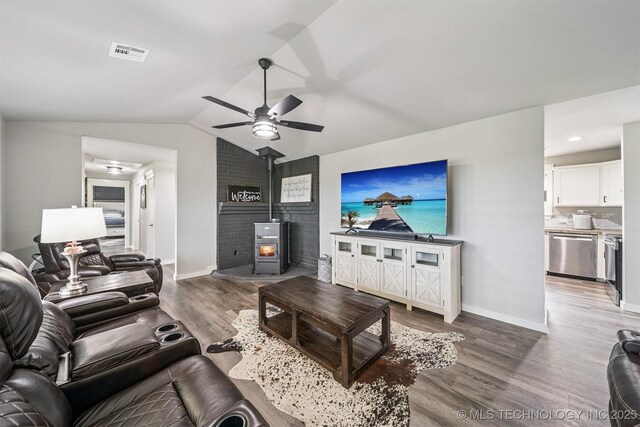 12929 N Sheridan Rd, Collinsville, OK 74021 - living room featuring a wood stove, wood finished floors, a ceiling fan, and vaulted ceiling