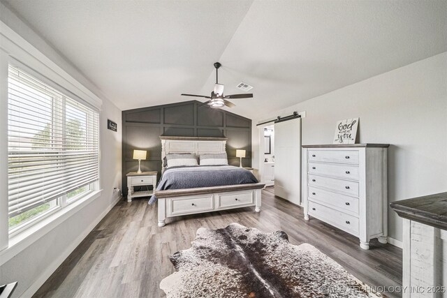 12929 N Sheridan Rd, Collinsville, OK 74021 - bedroom featuring wood finished floors, lofted ceiling, a barn door, and a ceiling fan