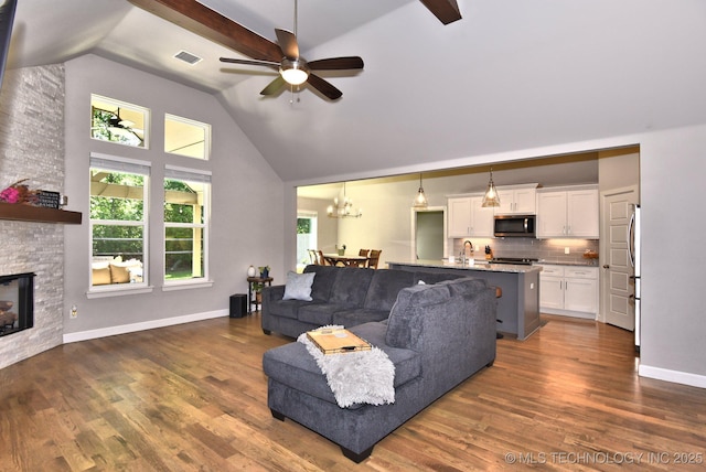 10423 S 233rd E Pl, Broken Arrow, OK 74014 - living area featuring high vaulted ceiling, a ceiling fan, a stone fireplace, dark wood-style flooring, and a chandelier