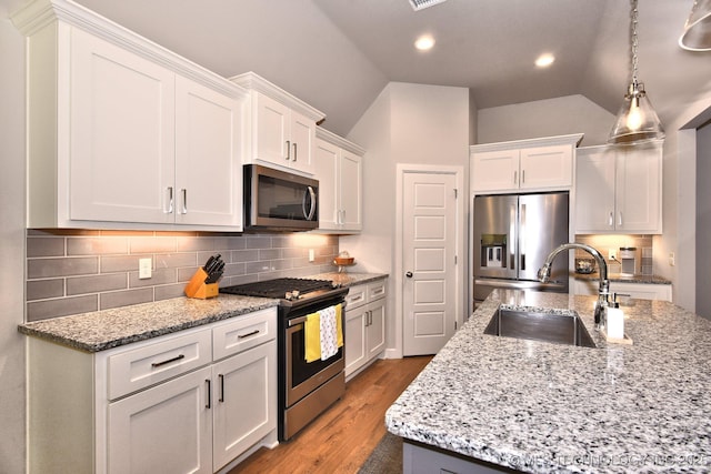 10423 S 233rd E Pl, Broken Arrow, OK 74014 - kitchen with stainless steel appliances, vaulted ceiling, white cabinetry, decorative backsplash, and wood finished floors