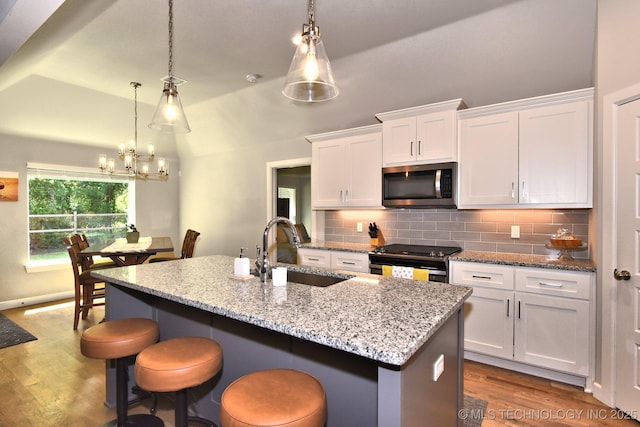 10423 S 233rd E Pl, Broken Arrow, OK 74014 - kitchen with stainless steel microwave, electric stove, white cabinets, wood finished floors, and vaulted ceiling