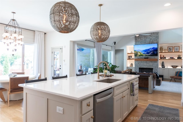 13661 S 23rd St, Bixby, OK 74008 - kitchen with stainless steel dishwasher, a chandelier, light wood-type flooring, a fireplace, and an island with sink