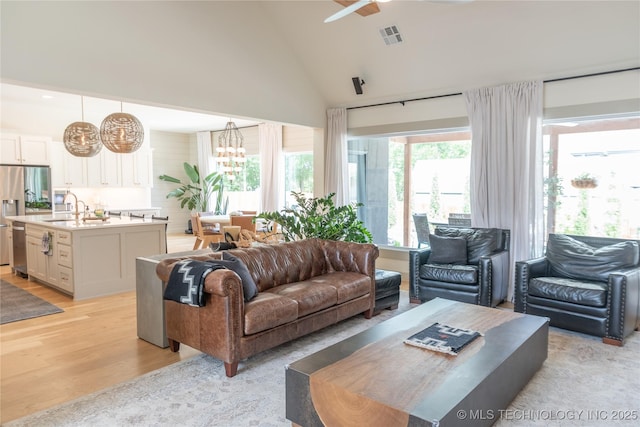 13661 S 23rd St, Bixby, OK 74008 - living area featuring light wood-type flooring, high vaulted ceiling, ceiling fan, and a chandelier
