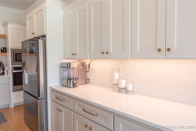 13661 S 23rd St, Bixby, OK 74008 - kitchen featuring stainless steel appliances, white cabinetry, decorative backsplash, light countertops, and light wood finished floors