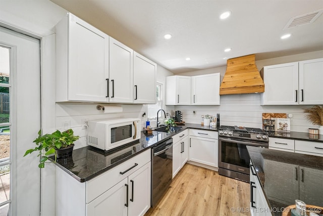 210 NW 4th St, Checotah, OK 74426 - kitchen with stainless steel gas range, custom exhaust hood, white microwave, dishwashing machine, and light wood finished floors