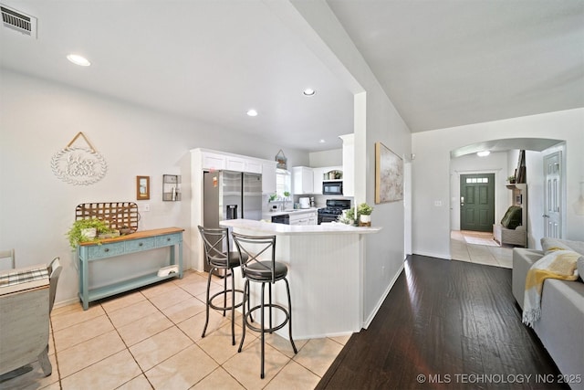 304 S 63rd St, Broken Arrow, OK 74014 - kitchen featuring black appliances, arched walkways, white cabinets, light countertops, and a peninsula