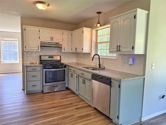 3610 Magnolia Dr, Sand Springs, OK 74063 - kitchen with appliances with stainless steel finishes, under cabinet range hood, wood finished floors, and decorative backsplash