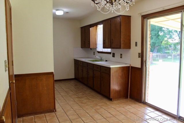 12329 E 18th St, Tulsa, OK 74128 - kitchen with light countertops, healthy amount of natural light, a chandelier, wainscoting, and light tile patterned floors