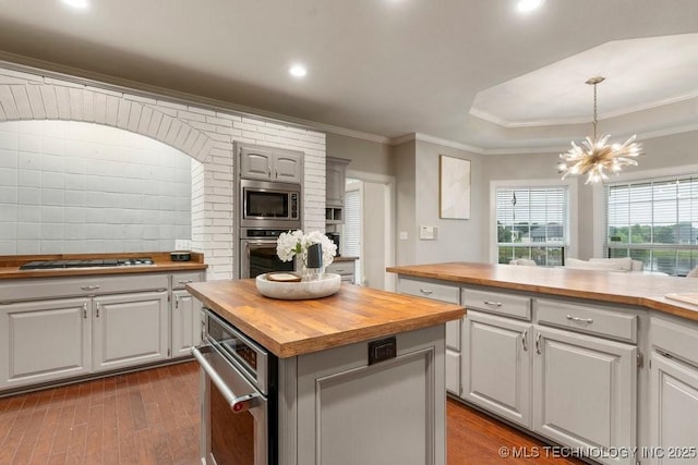 8766 Haskell Dr, Broken Arrow, OK 74014 - kitchen featuring butcher block countertops, appliances with stainless steel finishes, dark wood-style floors, a chandelier, and crown molding