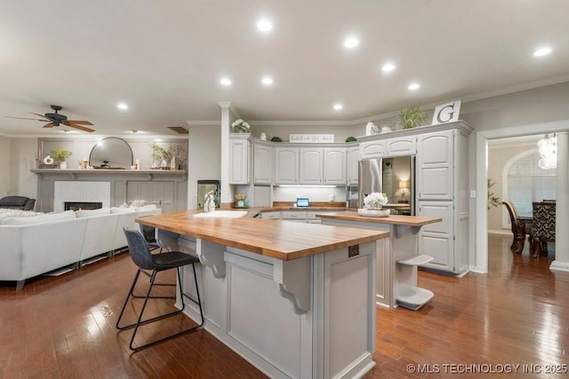 8766 Haskell Dr, Broken Arrow, OK 74014 - kitchen featuring wood counters, fridge, ornamental molding, a breakfast bar, and a kitchen island
