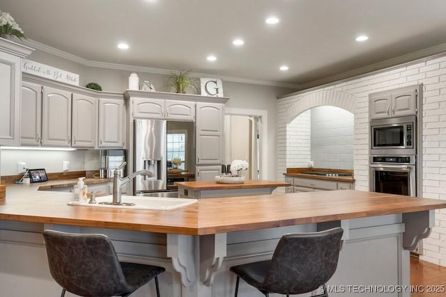 8766 Haskell Dr, Broken Arrow, OK 74014 - kitchen featuring wood counters, stainless steel appliances, a peninsula, recessed lighting, and a kitchen bar
