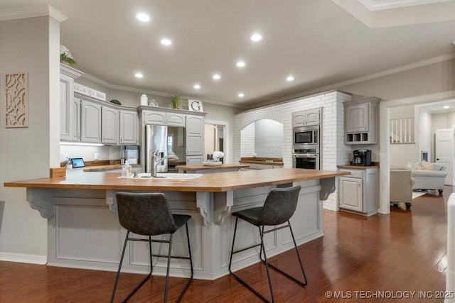 8766 Haskell Dr, Broken Arrow, OK 74014 - kitchen with wooden counters, a peninsula, stainless steel appliances, a kitchen breakfast bar, and recessed lighting