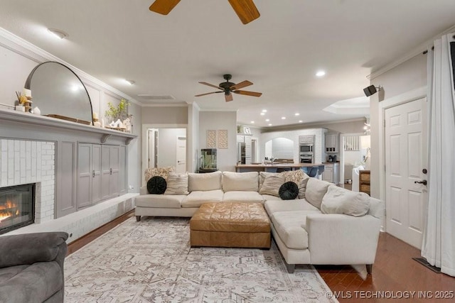 8766 Haskell Dr, Broken Arrow, OK 74014 - living room with ceiling fan, ornamental molding, wood finished floors, a brick fireplace, and recessed lighting