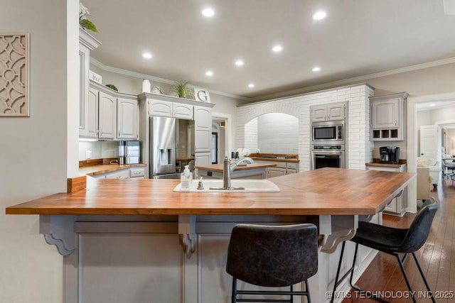8766 Haskell Dr, Broken Arrow, OK 74014 - kitchen featuring wooden counters, stainless steel appliances, ornamental molding, dark wood-style flooring, and a peninsula